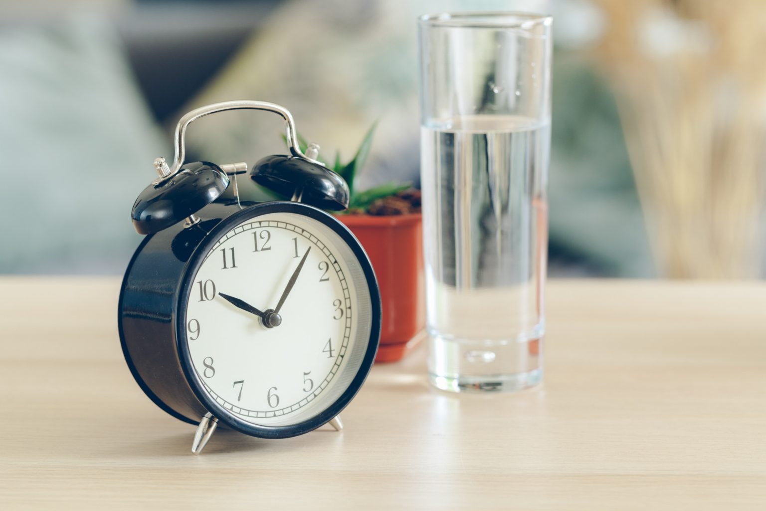 Vaso de agua junto a un reloj, representando la importancia de los pequeños cambios en casa para ahorrar agua y promover un estilo de vida sostenible.